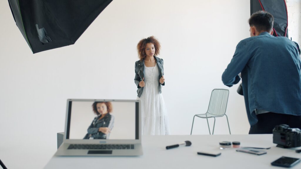 Model posing in studio with photographer and equipment